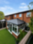 A brick house with a modern conservatory features a tiled roof and large windows