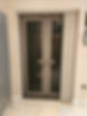 A closed patio door with vertical blinds partially open, revealing a bright room beyond