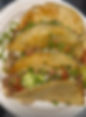 A plate of five tacos filled with seasoned meat, diced onions, cilantro