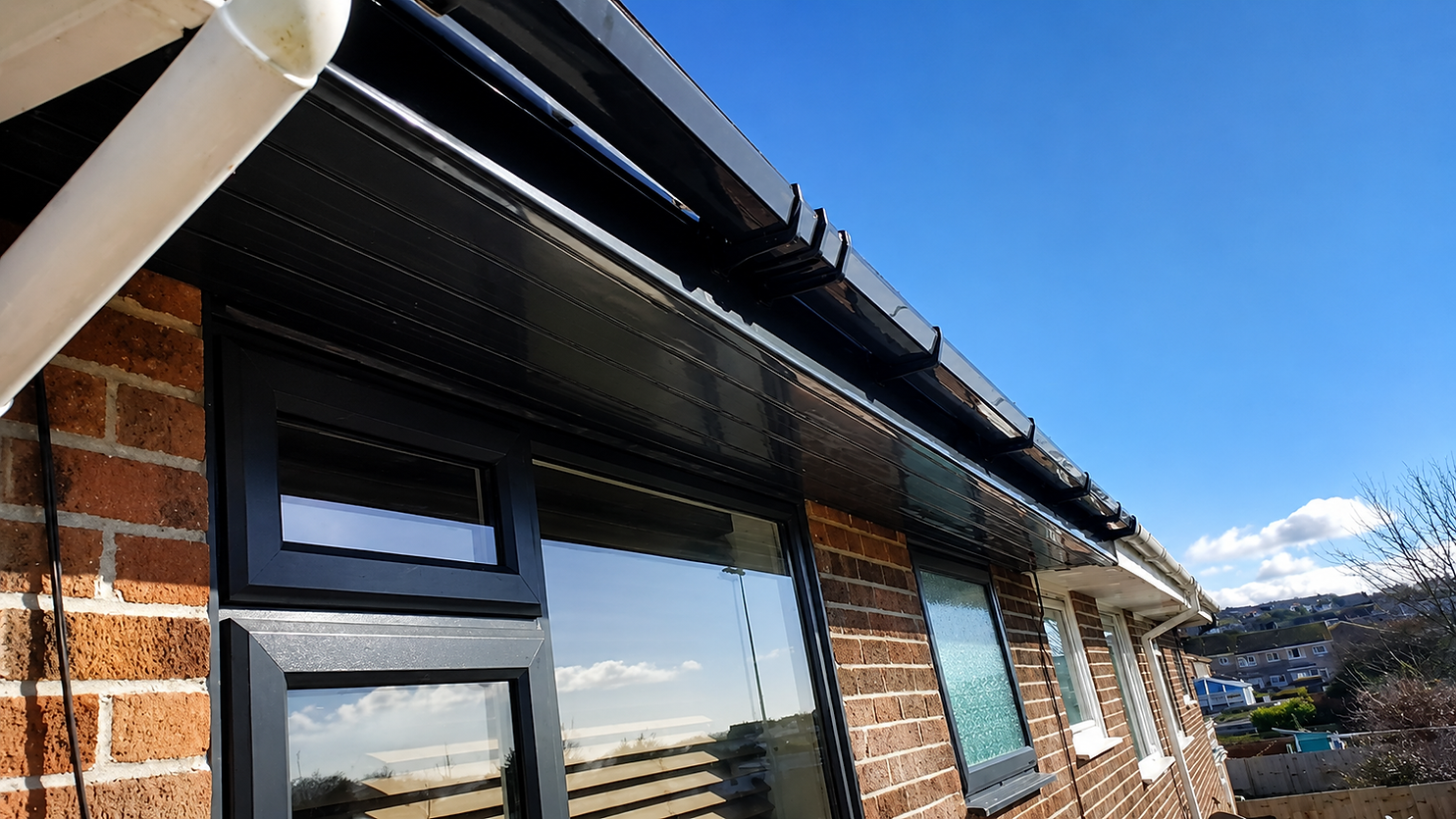  A black metal gutter attached to a house, with a window visible in the background