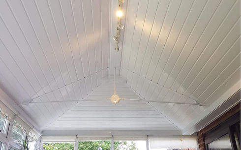White gabled ceiling with wooden panels and a ceiling fan