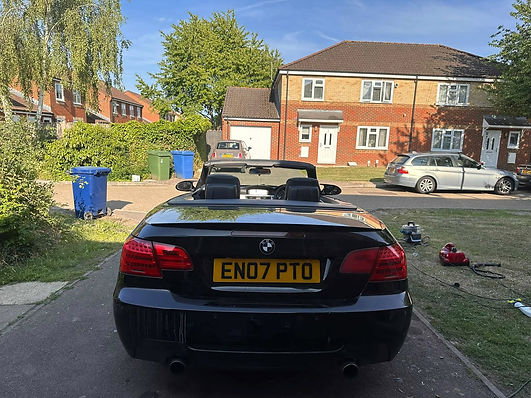 Rear view of a black convertible sports car with the roof down parked on a street