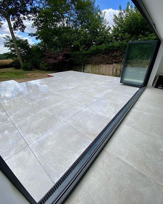 Modern grey porcelain patio slabs extending from a glass sliding door outdoor living area