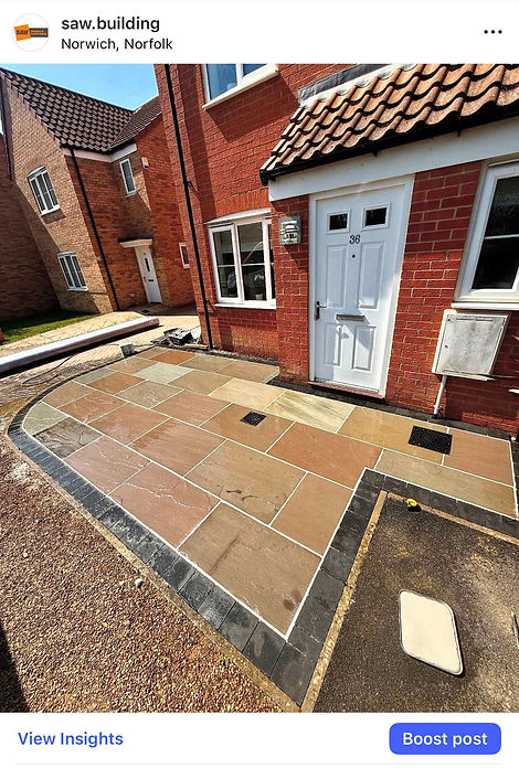 Newly laid sandstone patio with dark stone border outside a brick residential property