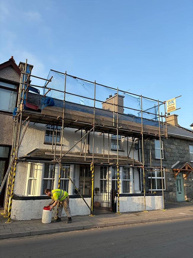 A white house with scaffolding covers the roof