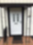 White door with decorative glass panels, black metal frame, and porch roof