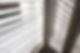 White blinds cast striped shadows across a sunlit wall