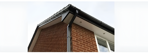 Low angle view of modern black uPVC guttering and downpipe installed on a red brick house with white soffits