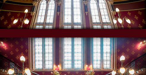 Stained glass windows in a grand room with decorative walls and ornate lighting fixtures.