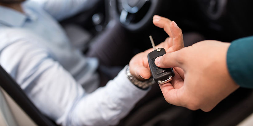 A hand passes car keys to another person, symbolizing trust and responsibility