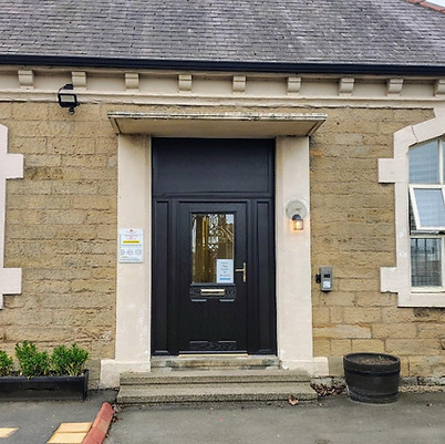 A stone building facade with two arched windows and a central black door