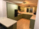 A modern kitchen with olive green cabinets, beige countertops, and tiled floor