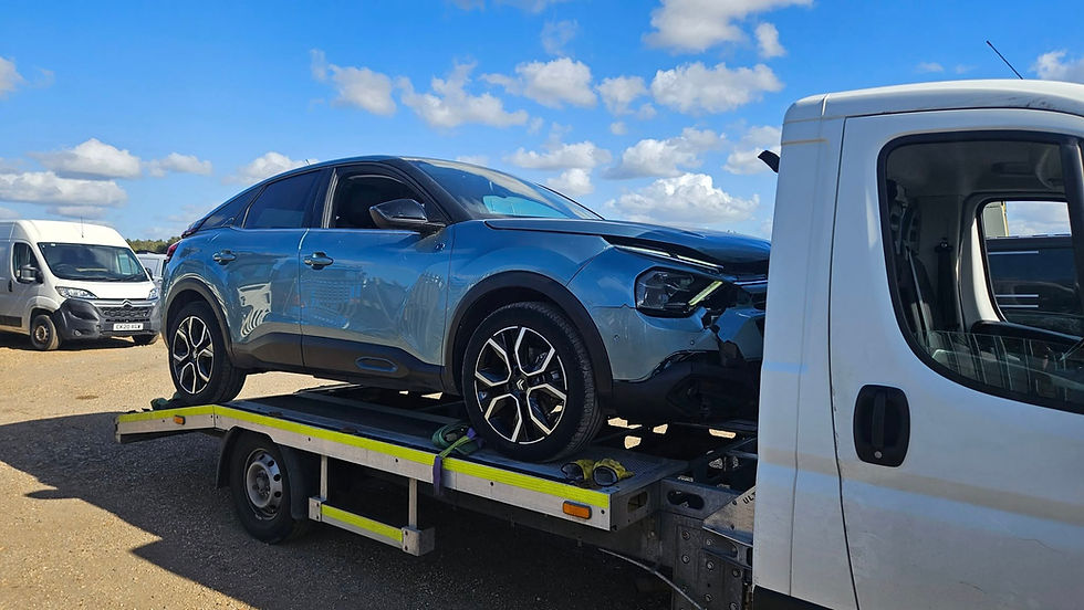 A blue car is being towed by a tow truck on a city street