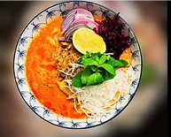 Thai Khao Soi curry noodle soup topped with lime red onion and fresh herbs in a pattern bowl