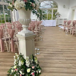 Elegant indoor wedding venue with white columns and floral arrangements of white and pink flowers