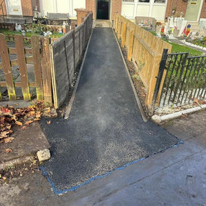 Tarmac garden path leading up to the front door of a residential property with a wooden fence