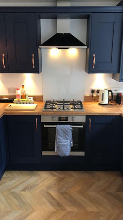 A kitchen with navy cabinets, wooden countertops