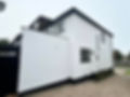 A modern white house with clean lines, featuring black-framed windows and a black gate