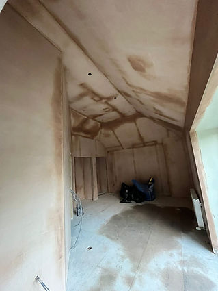 A small, empty attic room with freshly plastered walls and a slanted ceiling