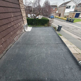 Flat roof with dark rubberized material adjacent to a brick house