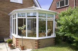 A bright conservatory with large windows, white frames