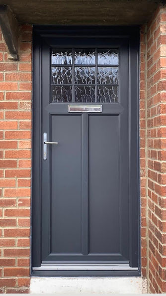 A dark gray front door with decorative glass panels at the top and a silver handle