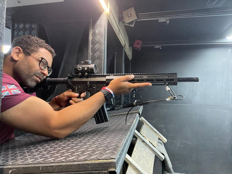 Man in a shooting range aiming a rifle with a focused expression