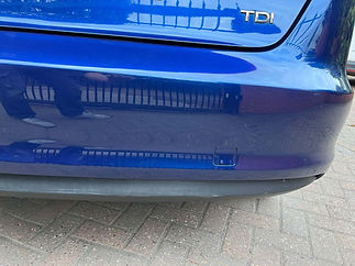 Close-up of a blue car's rear bumper with a "TDI" badge