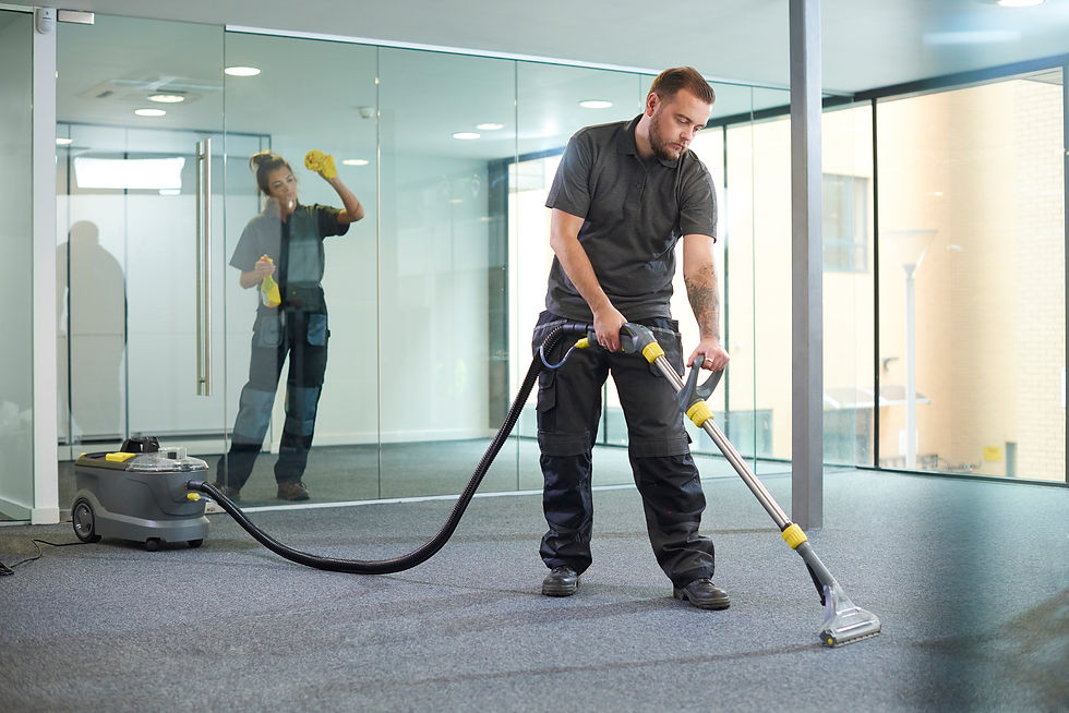 Professional cleaners using industrial equipment to clean a carpet and glass walls in a modern office