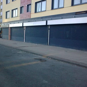 Long row of black security roller shutters on a street front building