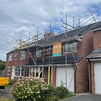 A two-story house with a mix of brick and red siding has scaffolding