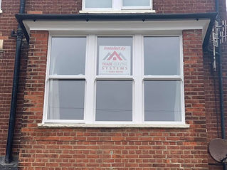 A brick building with white-framed windows features a sign