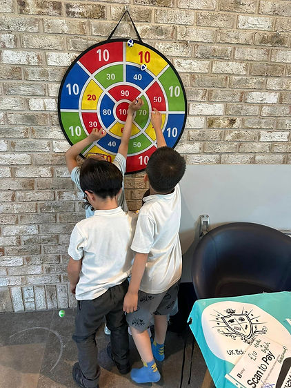 Children play darts on a colourful target board