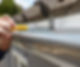 A person uses a yellow screwdriver to secure a metal gutter to a roof with brown tiles