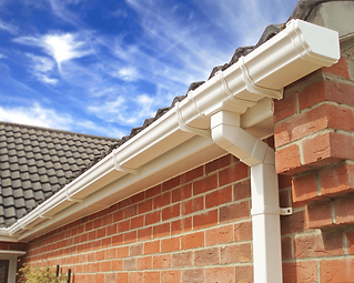 A white gutter system on a house with red brick walls and a gray tile roof