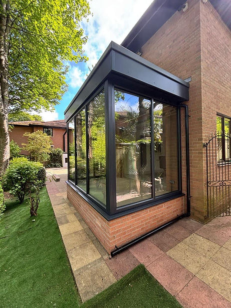 Brick house with a modern glass sunroom extension on a sunny day