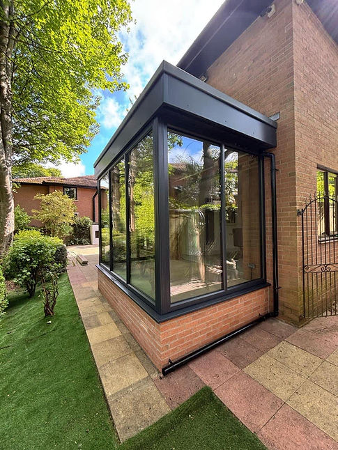A modern glass sunroom extends from a brick house
