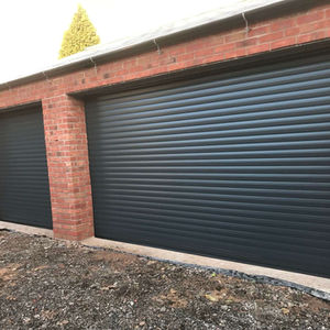 Two black roller garage doors on a red brick structure