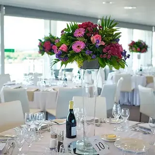 Elegant dining setup with tall floral centerpieces featuring purple and pink flowers