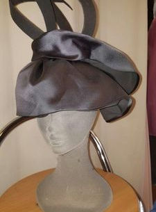 A stylish hat adorned with a bow displayed on a mannequin head.