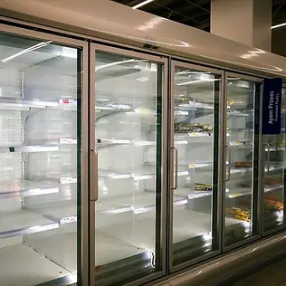 A grocery store freezer section with mostly empty shelves and a few remaining packaged items