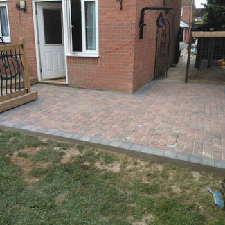 A newly paved brick patio extends from a red brick house