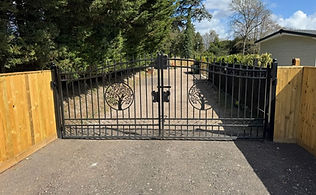 Open black metal driveway gates leading to a house