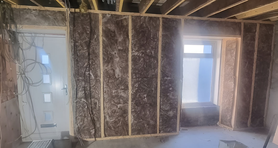 A room featuring a window and a wall fully covered in insulation material