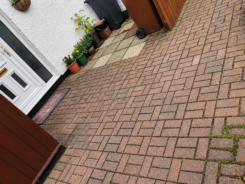 Red and charcoal herringbone block paving driveway leading up to a white house front door