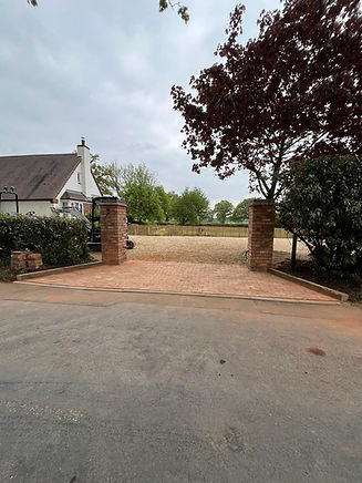 A brick driveway leads to a countryside house