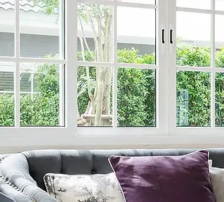 A gray sofa with a purple pillow sits by a large window