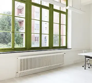 Bright room with large green-trimmed windows, white walls, and a radiator