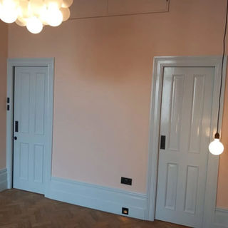 A softly lit room with light pink walls and white trim