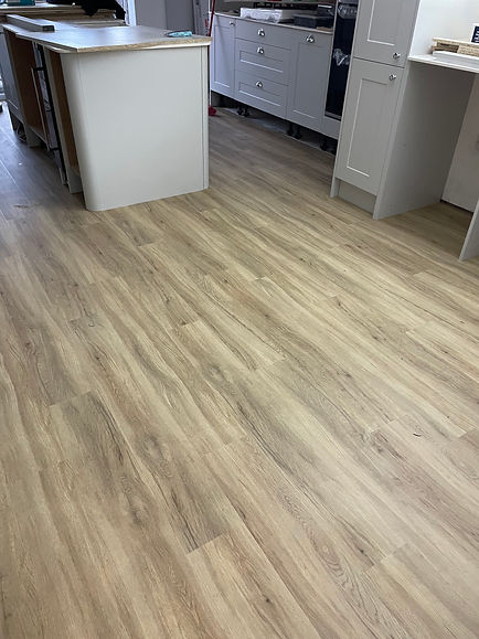 Wooden floored kitchen with light oak finish, featuring a central island and white cabinets